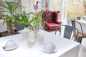 a white table with a vase of flowers on it at LLwyn Country House in Llanelli