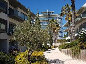 クアルテイラにあるCavalo Prеto Holiday apartment 200m to the beachのヤシの木と歩道のあるアパートメントビル