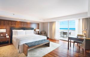 um quarto com uma cama grande e uma secretária e um quarto com vista em Windsor Marapendi Hotel no Rio de Janeiro