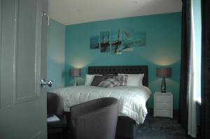 a bedroom with a bed with blue walls at Maryfield House Hotel in Lerwick