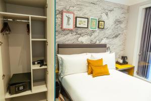 um quarto com uma cama com lençóis brancos e almofadas amarelas em Oliver Plaza Hotel em Londres