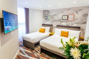ロンドンにあるオリバー プラザ ホテルのベッド2台とテレビが備わるホテルルームです。