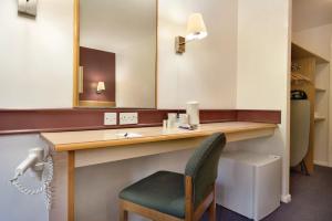 a bathroom with a vanity with a chair and a mirror at Days Inn Hotel Membury in Lambourn +20 photos