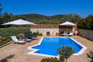 a pool with chairs and umbrellas in a yard at Alia Stone Villa-Ideal for families-Heated pool in Nohia