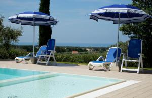 a group of chairs and umbrellas next to a pool at Agriturismo San Gregorio in San Vincenzo