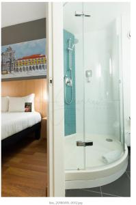 a bathroom with a glass shower with a bed at Hotel Ibis Lisboa Parque das Nações in Lisbon