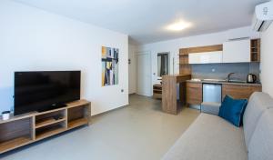a living room with a couch and a flat screen tv at Saint Lucas Suites in Nea Potidaea