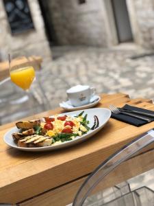 a plate of food on a table with a cup of orange juice at Bubalus Boutique Rooms in Trogir