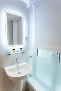 a bathroom with a sink, mirror, and bathtub at Oliver Plaza Hotel in London