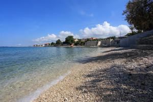 a beach with a rocky shore and the water at Pansion Marta in Bibinje