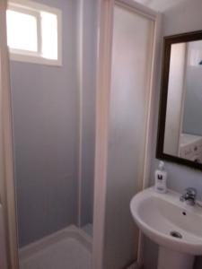 een badkamer met een douche, een wastafel en een spiegel bij Apartamento a la Playa in Algeciras
