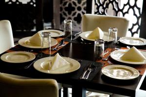 Rollace Hotel في إيكيجا: طاولة سوداء عليها صحون ومناديل بيضاء