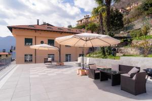 a patio with two umbrellas and a table and chairs at Al Pontile - The House Of Travelers in Sala Comacina