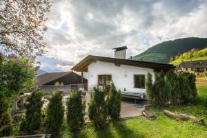 una pequeña casa blanca con un patio con árboles en Pardellerhof Ferienhaus, en Luson