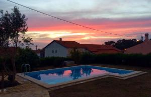 a swimming pool with a sunset in the background at Casas da Lagoa in Santo Isidoro