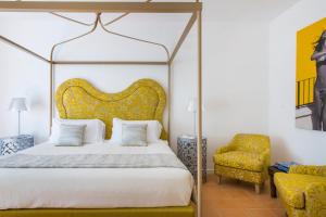 a bedroom with a canopy bed and a chair at Hotel Piccolo Sant'Andrea in Praiano