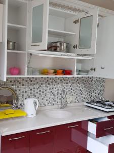 La cuisine est équipée de placards blancs et d'un évier. dans l'établissement Uzungol Comfort Residence, à Uzungöl
