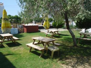 a group of picnic tables in a park with a tree at Bells Motel in Seferihisar