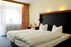 a bedroom with a large white bed with a black headboard at Hotel Prinzen in Kappelrodeck