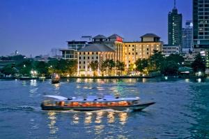 a boat on a river with a city at night at Ibis Bangkok Riverside in Bangkok