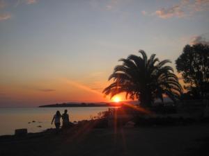 2 personnes marchant sur la plage au coucher du soleil dans l'établissement Bells Motel, à Seferihisar
