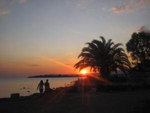 two people walking on the beach at sunset at Bells Motel in Seferihisar