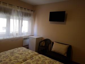 a bedroom with a bed and a chair and a television at Pensión Arenal in San Vicente de la Barquera