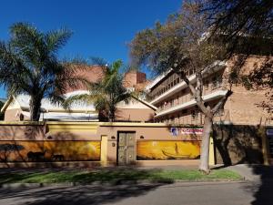 a building with a wall with a door and palm trees at Chisam Guest Lodge Pty Ltd in Johannesburg