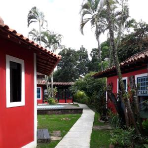 una casa roja con palmeras en un patio en Pousada Maria da Toca, en Rio das Ostras