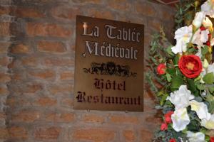 um sinal numa parede de tijolos com flores em La Tablée Médiévale em Civrieux-dʼAzergues