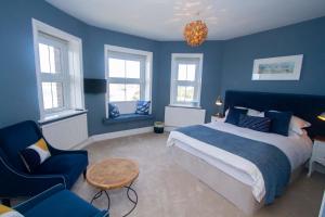 ニューキーにあるクリフ ハウスの青い壁のベッドルーム1室、ベッド1台、テーブルが備わります。