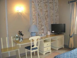 a bedroom with a desk with a television and a bed at Auberge des Lices in Carcassonne