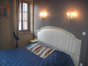 um quarto com uma cama com um edredão azul e uma janela em Auberge des Lices em Carcassonne
