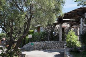 a stone house with a stone wall and a tree at Casa Valery Wonderful Sea View in Porto Rotondo