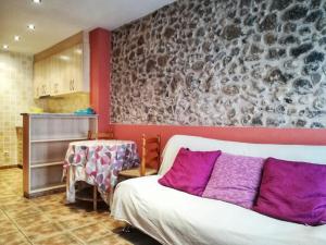 1 dormitorio con cama blanca y almohadas moradas en El Balco del Llierca, en Sant Jaume de Llierca