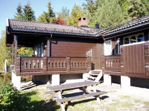 a wooden cabin with a picnic table in front of it at Hogstul Hytter - Knatten - 3 Bedroom Cottage in Tuddal