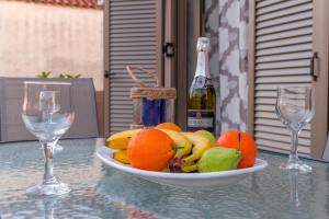a bowl of fruit on a table with two wine glasses at Nadia Studios in Kalamaki