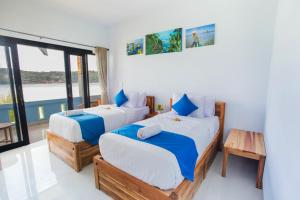 two beds in a room with a view of the water at Aurora Beach View in Nusa Lembongan