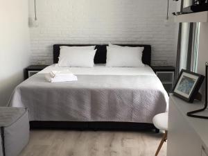 una camera da letto con un letto con lenzuola bianche e cuscini bianchi di Athens View Loft - 01 ad Atene