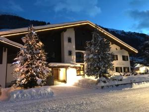 a house with snow covered trees in front of it at Hotel Dr Otto Murr B&B in Sankt Anton am Arlberg