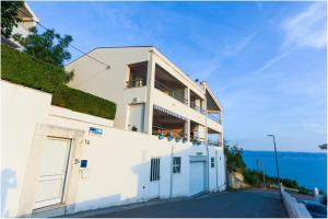 a white building with a balcony on the side of it at Apartments Maja in Podstrana