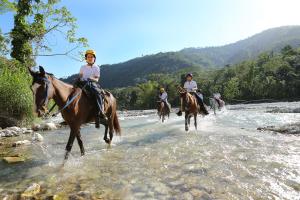 a group of people riding horses across a river at Platon Ecolodge in Santa Cruz de Barahona