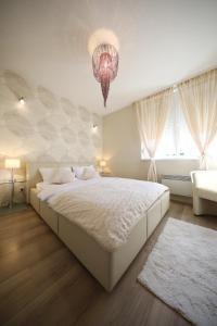 Un dormitorio con una gran cama blanca y una lámpara de araña. en Top Apartments Zadar, en Zadar
