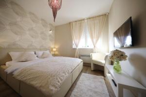 1 dormitorio con 1 cama, TV y silla en Top Apartments Zadar, en Zadar