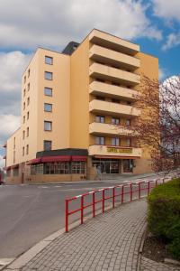 a large building with a red fence in front of it at Hotel Merkur - Jablonec nad Nisou in Jablonec nad Nisou