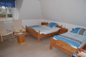 a bedroom with two beds and a chair and a window at Haus Karen in Schafflund