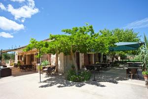 een patio met tafels en stoelen en een groene parasol bij Agroturisme Na Martina in Portopetro