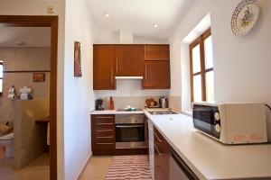 a kitchen with wooden cabinets and a microwave on a counter at Agroturisme Na Martina in Portopetro