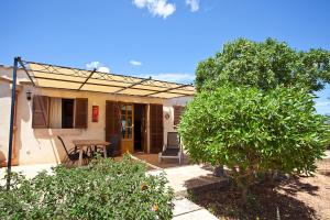 a small house with a table and a tree at Agroturisme Na Martina in Portopetro