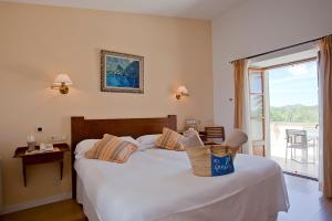 a bedroom with a large white bed with a window at Agroturisme Na Martina in Portopetro